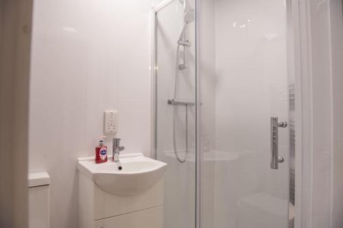 La salle de bains blanche est pourvue d'un lavabo et d'une douche. dans l'établissement One bedroom Studio: Old Trafford, à Manchester