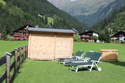a group of chairs sitting in a field with a building at Berghaus Martin in Neustift im Stubaital