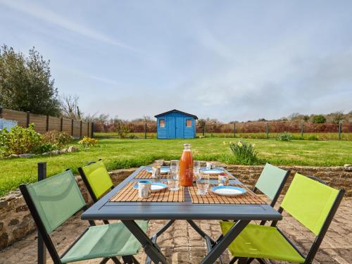 Una mesa con sillas y una casa azul al fondo. en Holiday Home Le Hameau Boudet by Interhome, en Barneville-Carteret