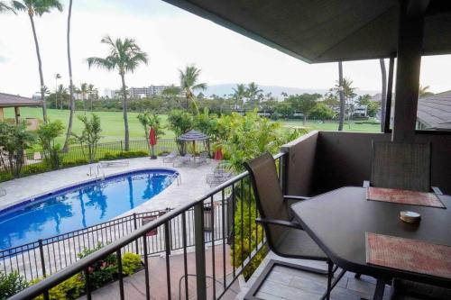 a balcony with a table and a swimming pool at Maui Bliss: 1BR Corner Haven, Ocean & Golf Views in Kahana