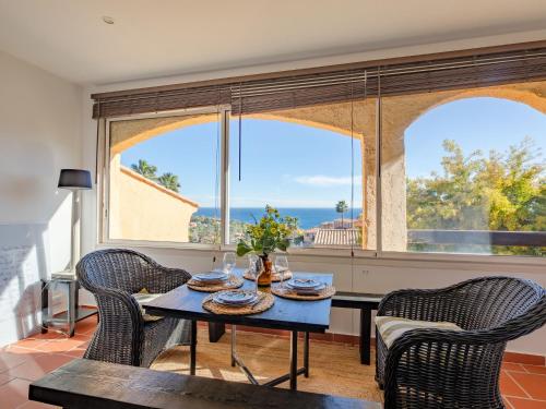 une salle à manger avec une table, des chaises et des fenêtres dans l'établissement Studio Les Mimosas by Interhome, à Théoule-sur-Mer