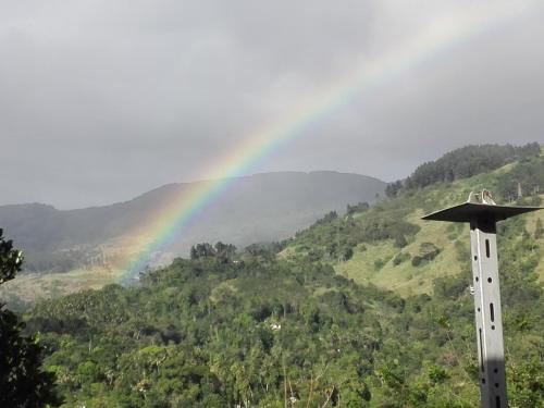 a rainbow over a hill with a pole with a cross at Lanka Peter's House Tourist Guest House & Restaurant in Peradeniya