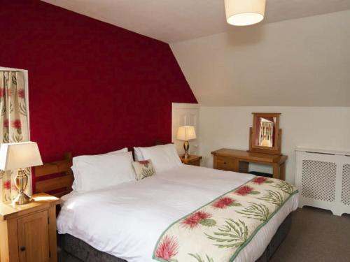a bedroom with a white bed with a red wall at Holiday Home Oakdale House by Interhome in Drumnadrochit