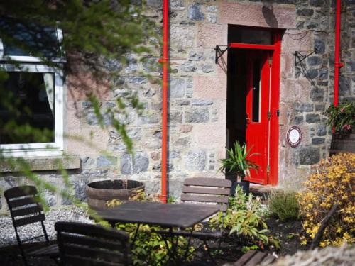 a red door of a building with a table and chairs at Holiday Home Oakdale House by Interhome in Drumnadrochit