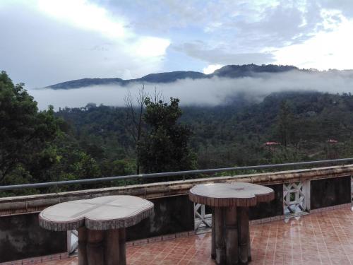 a balcony with two tables and a view of the mountains at Lanka Peter's House Tourist Guest House & Restaurant in Peradeniya