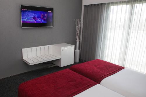 a hotel room with a bed and a television at Hotel Costa Verde in Póvoa de Varzim