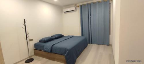 1 dormitorio con cama con sábanas azules y ventana en Shitha Inn en Hithadhoo
