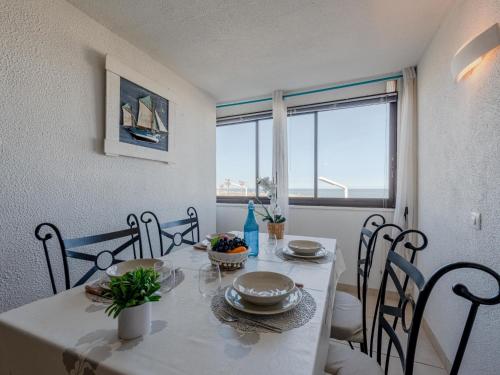 une salle à manger avec une table et des chaises blanches ainsi qu'une fenêtre dans l'établissement Apartment Front de Mer-25 by Interhome, au Barcarès
