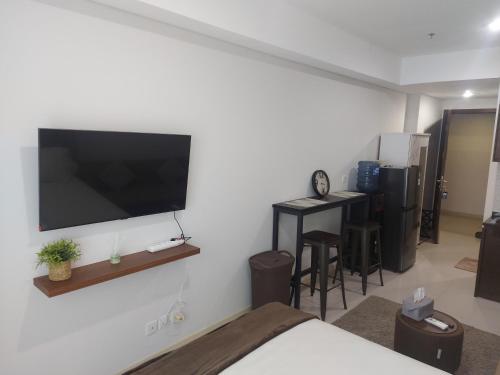 Comfy Studio with City View @BorneoBay Residence في Klandasan Kecil: غرفة مع تلفزيون بشاشة مسطحة على الحائط