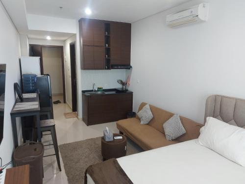 a room with a bed and a couch and a kitchen at Comfy Studio with City View @BorneoBay Residence in Klandasan Kecil