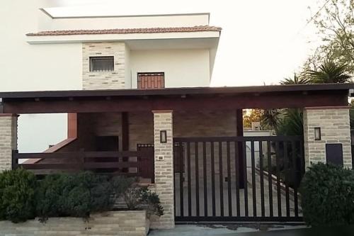 ein Haus mit einem Tor und einem Balkon in der Unterkunft Casa vacanze a 100mt dal mare in Torre Ovo