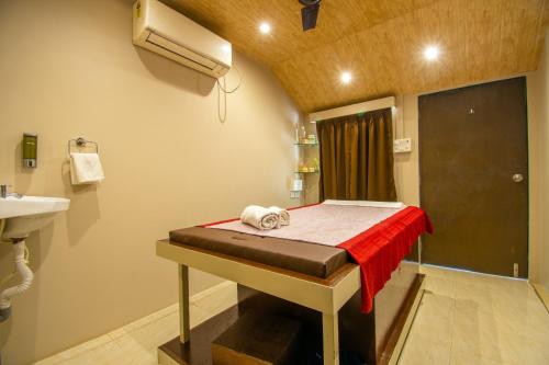a room with a bed with a red blanket and a sink at Flora Ecostay Resort and Spa Lonavala in Lonavala