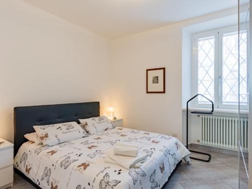 a white bedroom with a bed with a black headboard at Apartment Bina by Interhome in Bellano