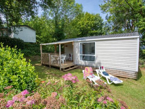 Une petite maison blanche avec deux chaises et une terrasse couverte dans l'établissement Holiday Home Prestige 2 chambres 5 personnes by Interhome, à Payrac