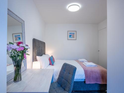 ein Schlafzimmer mit einem Bett und einer Vase aus Blumen auf einem Tisch in der Unterkunft Studio Harbour Nights 7B by Interhome in Lossiemouth