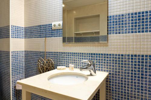 uma casa de banho em azulejos azuis com um lavatório e um espelho em Suite Andrés Pérez Málaga Center em Málaga