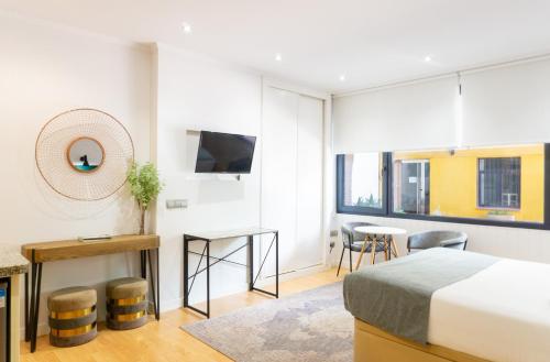 um quarto com uma cama e uma sala de estar com uma mesa em Suite Andrés Pérez Málaga Center em Málaga