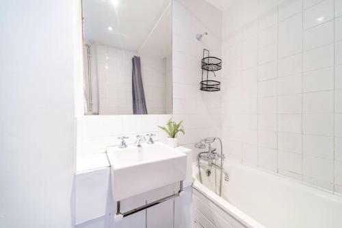 a white bathroom with a sink and a bath tub at Beautiful one bedroom flat in Tavistock Place in London