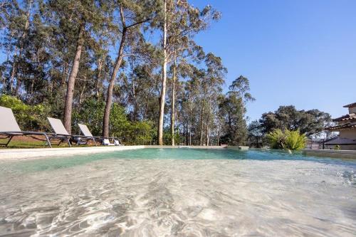 a swimming pool with some chairs and trees at Villa da floresta in Arcos