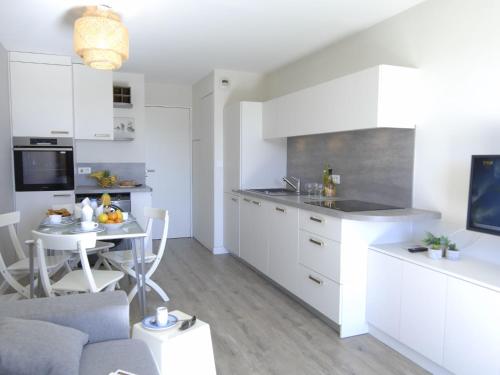 une cuisine avec des armoires blanches et une table dans une pièce dans l'établissement Apartment Le Village - VJ 107 by Interhome, à Agay