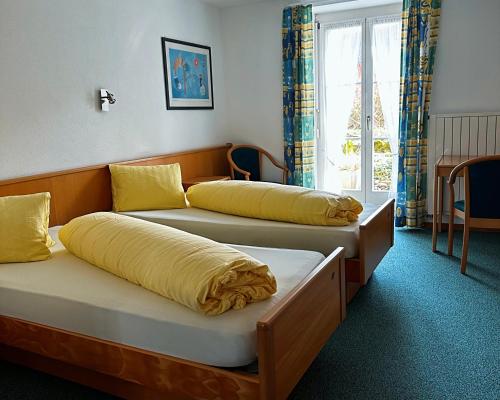 2 łóżka w pokoju z żółtymi poduszkami w obiekcie Hotel Löwen w mieście Mönchaltorf