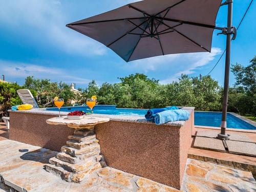 uma mesa com um guarda-sol ao lado de uma piscina em Holiday Home Marija by Interhome em Kaštel Novi