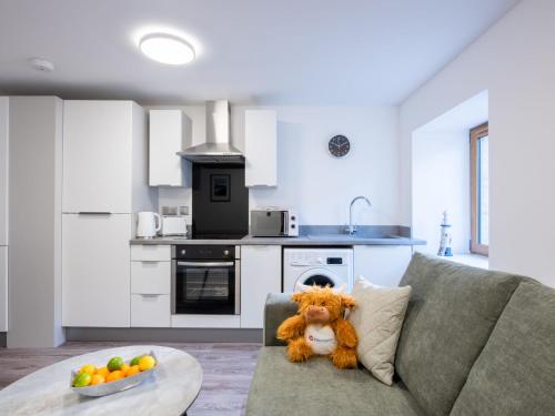a teddy bear sitting on a couch in a kitchen at Studio Harbour Nights 7A by Interhome in Lossiemouth