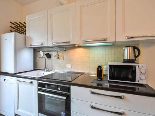 uma cozinha com armários brancos, um lavatório e um micro-ondas em Apartment Olmo Garden Apartment by Interhome em Morbegno