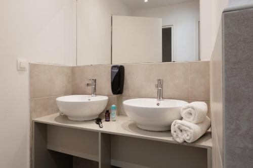 a bathroom with two sinks and a mirror and towels at Local Hostel & Suites in Corfu Town