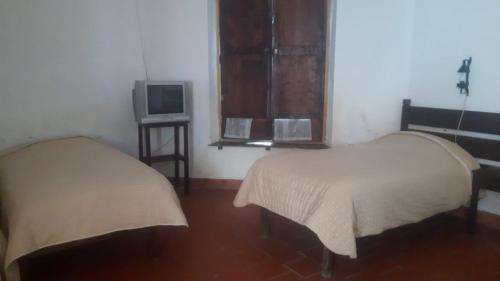 a room with two beds and a tv in it at Cruz Popayan Sucre in Sucre