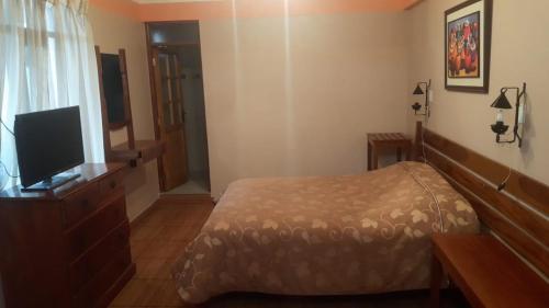 a bedroom with a bed and a flat screen tv at Cruz Popayan Sucre in Sucre