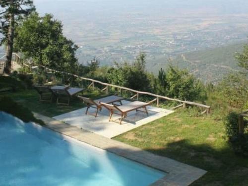 a swimming pool with a table and benches on a hill at Holiday Home Bellavista by Interhome in Cortona