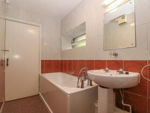 y baño con lavabo, espejo y bañera. en Ground Floor Apartment en Porthmadog