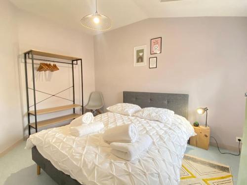 une chambre avec un lit avec des draps blancs et des oreillers dans l'établissement Le Cathédrale,T3 en plein centre ville de Poitiers, à Poitiers