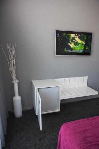 a white bench in a room with a tv on the wall at Hotel Costa Verde in Póvoa de Varzim