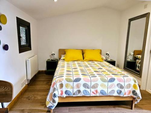 a bedroom with a bed with yellow pillows and a mirror at Treetops Lodge, private parking & garden in Truro