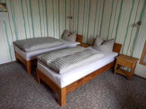 two twin beds in a room with two tables at Pension Volgenandt in Breitenbach