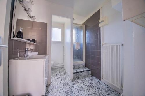 y baño blanco con lavabo y ducha. en Trioasis - 3 chambres, en Reims