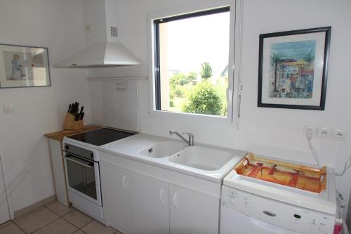 une cuisine blanche avec un évier et une fenêtre dans l'établissement Maison 8p sud bretagne 5km de la mer, à Saint-Molf