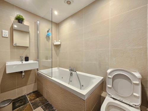 a bathroom with a tub and a toilet and a sink at Delightful 2 Bedroom Apartment! in London