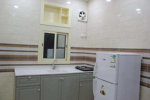 La cuisine est équipée d'un évier et d'un réfrigérateur blanc. dans l'établissement دار الكيان للشقق المخدومة - Dar Al Kayan Serviced Apartments, à Djeddah