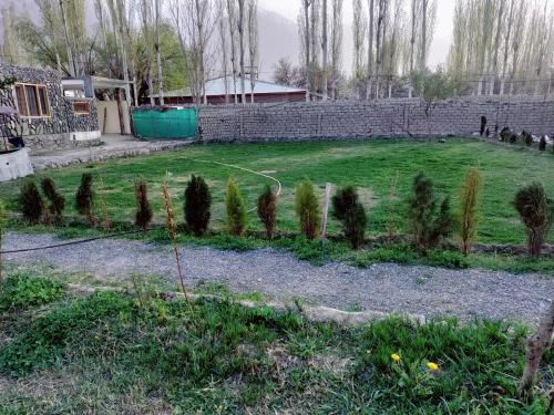 um jardim com árvores e uma parede de tijolos em Baltistan Sarayee hotel £ Guest House em Skardu