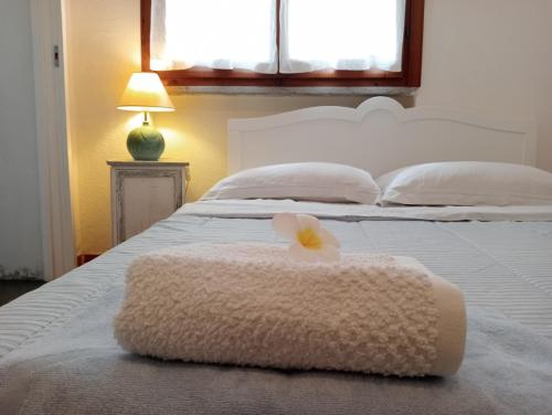 a white bed with a white blanket with a flower on it at Casa Helichrysum in Forte Village