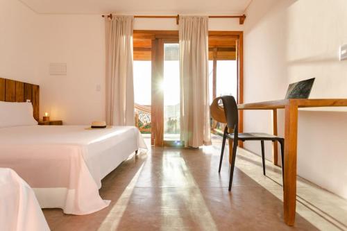 a bedroom with a bed and a desk and a window at Casa Nós de Vento - Praia do Prea in Cruz