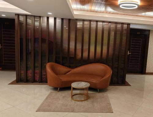 a brown couch and a table in a lobby at Hotel GRT Square in Dhārwād