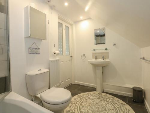 a white bathroom with a toilet and a sink at Abbey Cottage in Newball