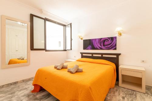 una camera da letto con un letto con una coperta arancione di Sunset view 3 a Puerto de Santiago