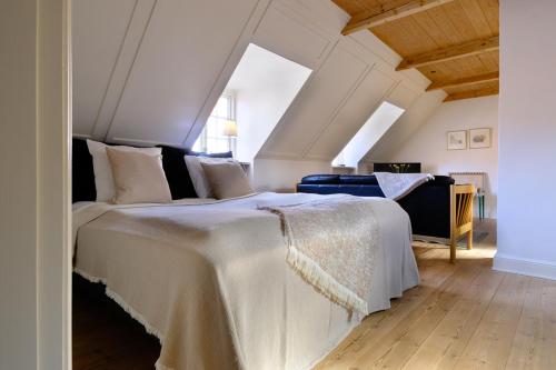 ein Schlafzimmer mit einem großen weißen Bett im Dachgeschoss in der Unterkunft Købmandsgaarden Kerteminde in Kerteminde