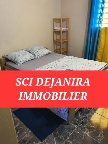 Cama en habitación con una pancarta roja en DEJANIRA IMMOBILIER, en Saint-Laurent-du-Maroni