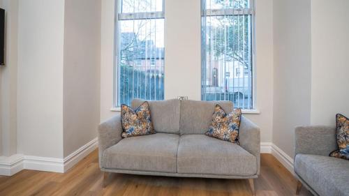 a living room with a couch and two windows at Modern 2 BDR apartment at Queens by Belfast City Breaks in Belfast